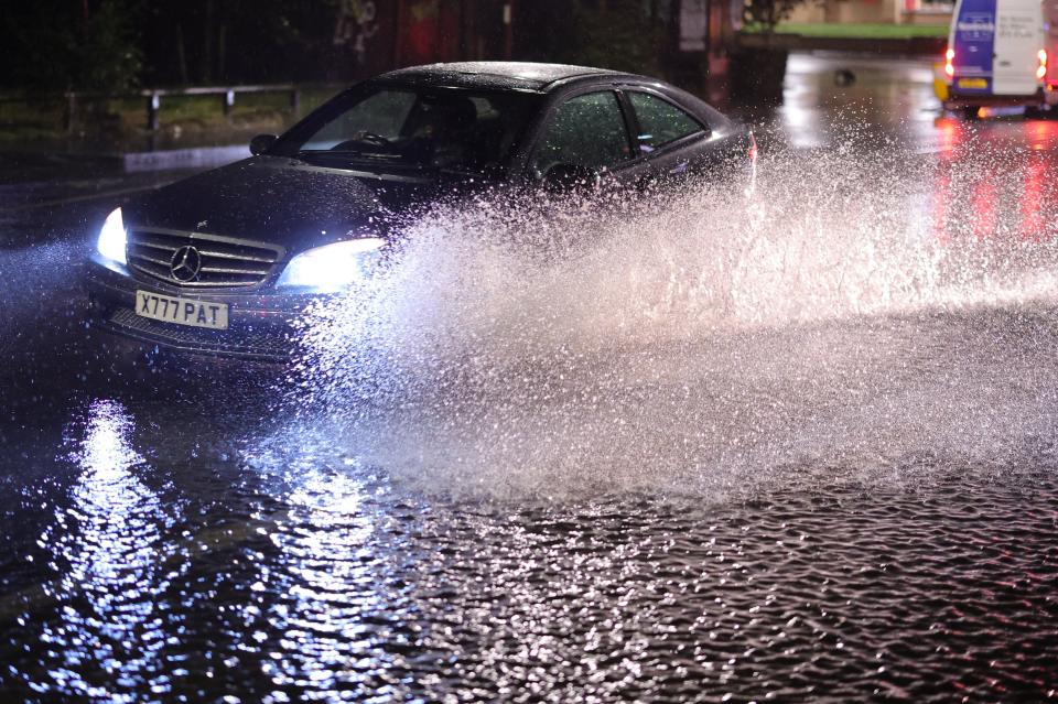 Vehicles make a splash as they are driven through a section of partially flooded road following torrential rain in Colliers Wood (George Cracknell Wright)