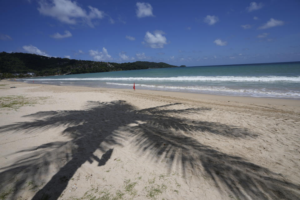 A palm tree casts a shadow on the empty tourist beach of Patong on Phuket, southern Thailand, Monday, June 28, 2021. Thailand's government will begin the "Phuket Sandbox" scheme to bring the tourists back to Phuket starting July 1. Even though coronavirus numbers are again rising around the rest of Thailand and prompting new lockdown measures, officials say there's too much at stake not to forge ahead with the plan to reopen the island to fully-vaccinated travelers. (AP Photo/Sakchai Lalit)