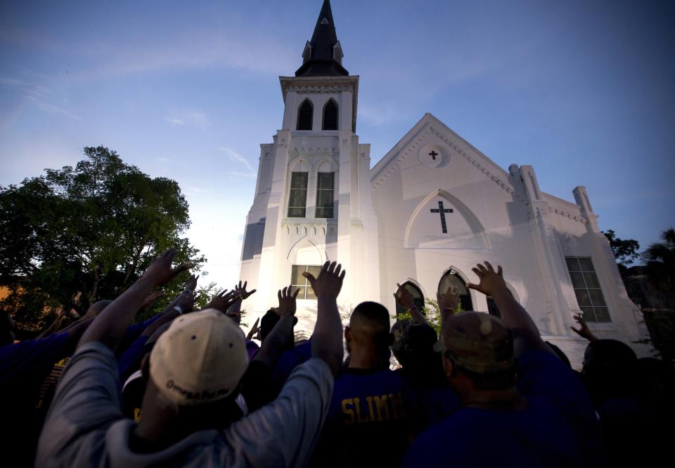 FILE - The men of Omega Psi Phi Fraternity Inc., lead a crowd of people in prayer outside the Emanuel AME Church on June 19, 2015, after a memorial in Charleston, S.C. Thousands gathered at the College of Charleston TD Arena to bring the community together after nine people where shot to death at the church days prior. After mass shootings, the loss felt by marginalized groups already facing discrimination is compounded. Some public health experts say the risk for post-traumatic stress disorder is greater for the groups, especially when the shootings take place at schools, churches and other vital hubs. (AP Photo/Stephen B. Morton, File)