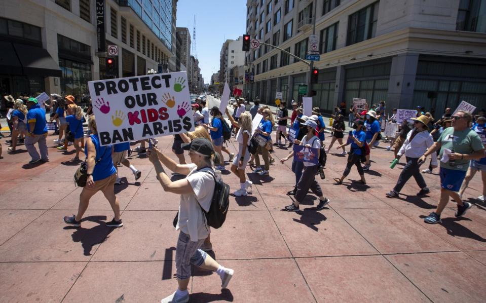 Marchers pass through an intersection lined by multistory buildings.