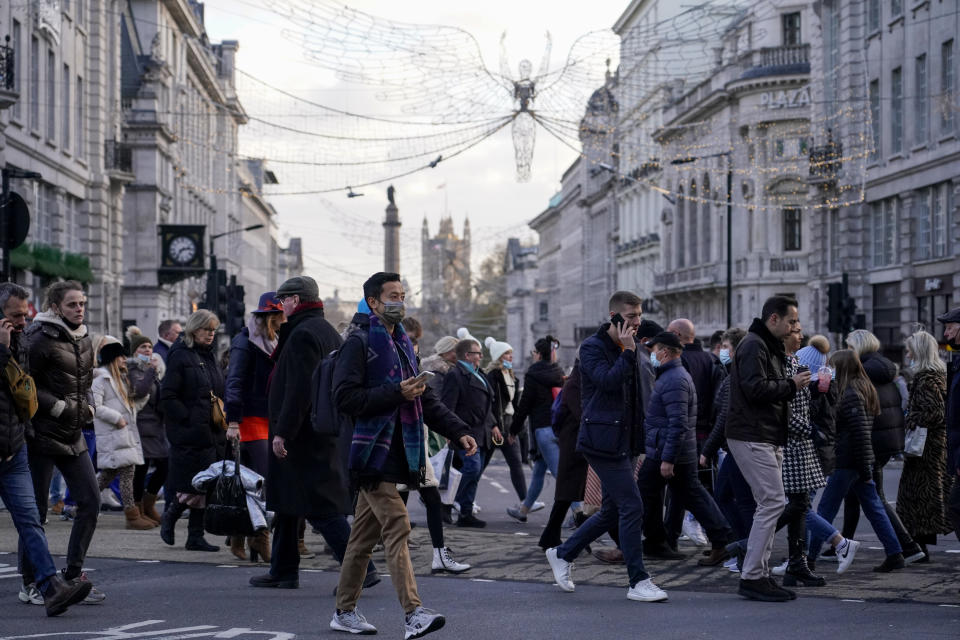 A person wears a face mask while crossing a road in Piccadilly Circus, in London, Saturday, Dec. 4, 2021. Britain says it will offer all adults a booster dose of vaccine within two months to bolster the nation's immunity as the new omicron variant of the coronavirus spreads. New measures to combat variant came into force in England on Tuesday, with face coverings again compulsory in shops and on public transport. (AP Photo/Alberto Pezzali)