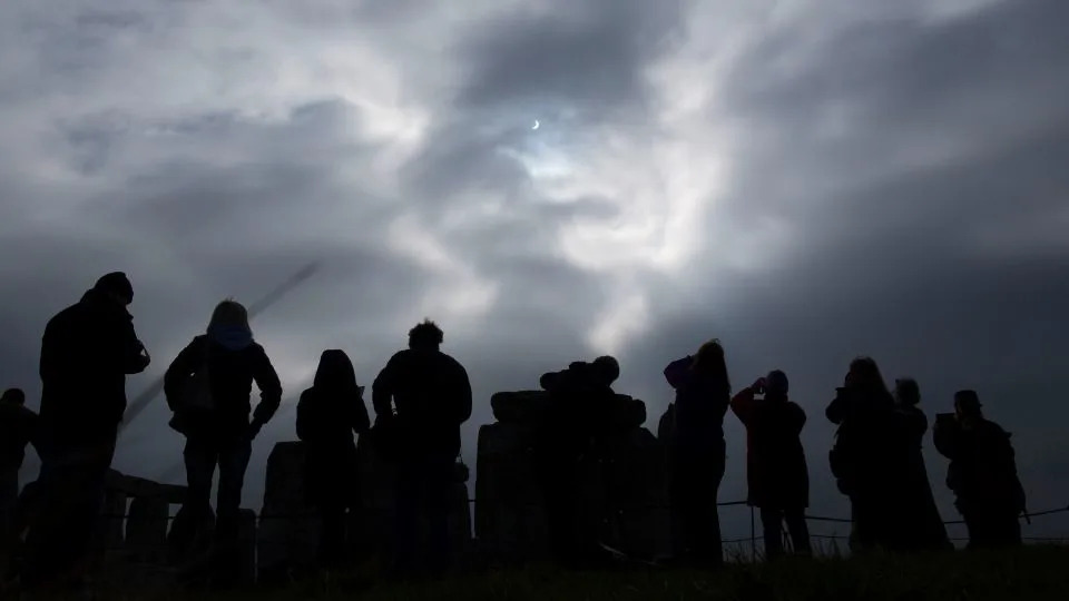 A small gap in a layer of overcast clouds allows visitors view a solar eclipse from Stonehenge in southern England on March 20, 2015. - Kieran Doherty/Reuters