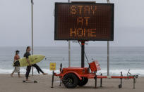 A surfer carries his board as he skates along the beach front at Manly on the northern beaches in Sydney, Australia, Monday, Dec. 21, 2020. Sydney's northern beaches are in a lockdown similar to the one imposed during the start of the COVID-19 pandemic in March as a cluster of cases in the area increased to more than 80. (AP Photo/Mark Baker)