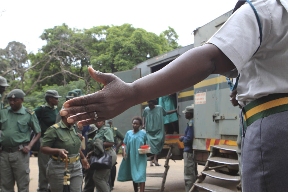 A prison guard directs some of the people arrested during protests over the hike in fuel prices, as they arrive to make their magistrates court appearance in Harare, Zimbabwe, Thursday, Jan, 17, 2019. A Zimbabwe Lawyers for Human Rights says in a statement that pastor and activist Evan Mawarire who is among the more than 600 people arrested this week has been charged with subverting a constittutional government amid a crackdown on protests against a dramatic fuel price increase.(AP Photo/Tsvangirayi Mukwazhi)