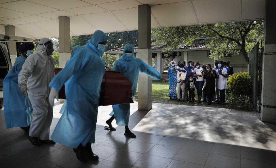 A Sri Lankan Christian family grieves as municipal cemetery workers carry the body of their family member who died of COVID-19 for cremation in Colombo, Sri Lanka, Friday, Dec. 11, 2020. (AP Photo/Eranga Jayawardena)