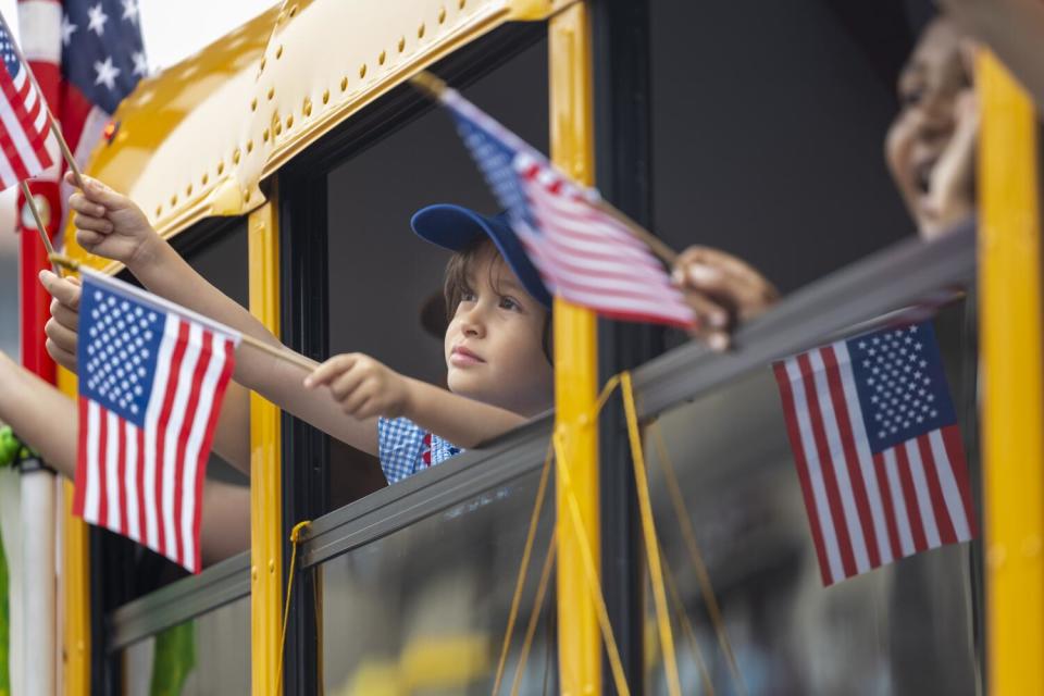 Kids wave flags while participating in the Huntington Beach Annual Independence Day Parade.