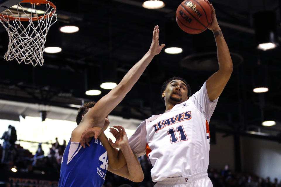 Pepperdine guard Keith Smith (11) grabs a rebound next to BYU guard Connor Harding (44) during the first half of an NCAA college basketball game Saturday, Feb. 29, 2020, in Malibu, Calif. (AP Photo/Ringo H.W. Chiu)