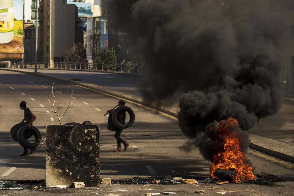 Protesters burn tires to close the main road, after the Lebanese pound hit a record low against the dollar on the black market, in Beirut, Lebanon, Saturday, March 6, 2021. (AP Photo/Hassan Ammar)