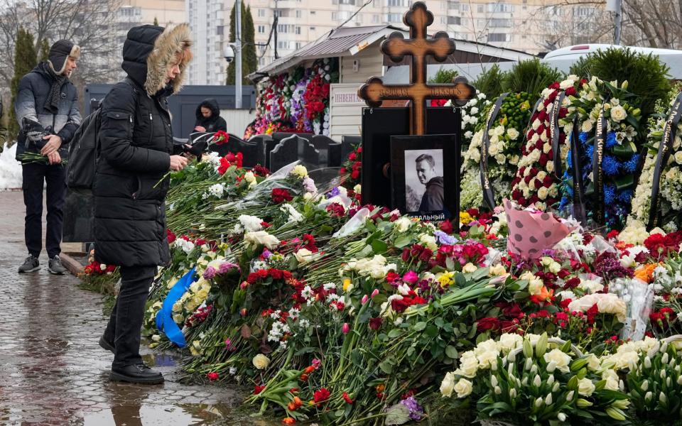 A woman lays flowers at the grave of Alexei Navalny a day after his funeral at the Borisovskoye Cemetery