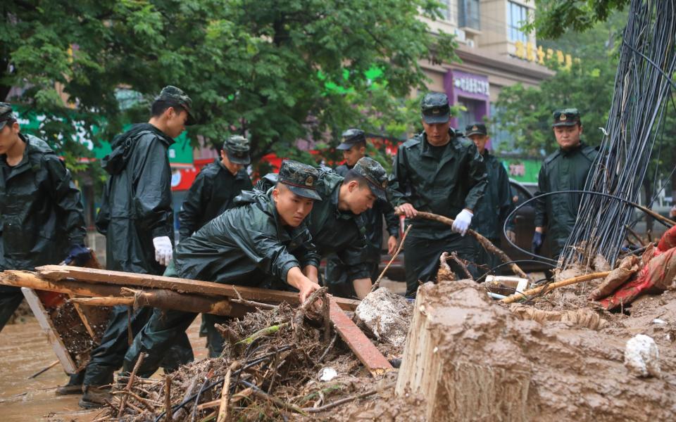 Paramilitary police officers clear debris on a street affected by floods due to heavy rainfall in Gongyi city, Henan - REUTERS 