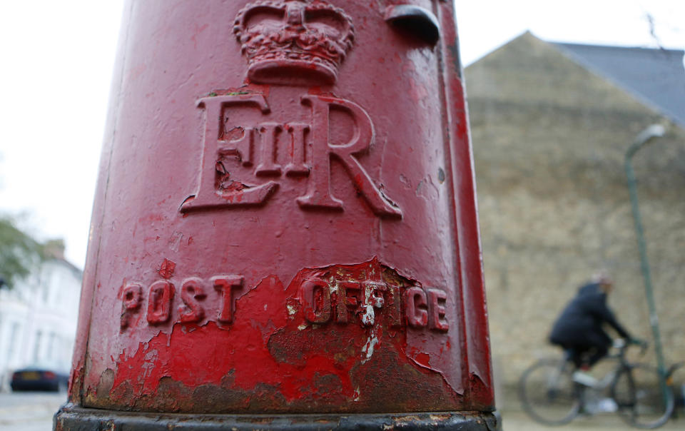 A man rides a bicycle past a post box in London November 27, 2013. Britain's Royal Mail said rising parcel revenue and ongoing cost cuts helped the newly-privatised postal operator almost double its operating profit in the first half of the year.   REUTERS/Suzanne Plunkett (BUSINESS EMPLOYMENT)