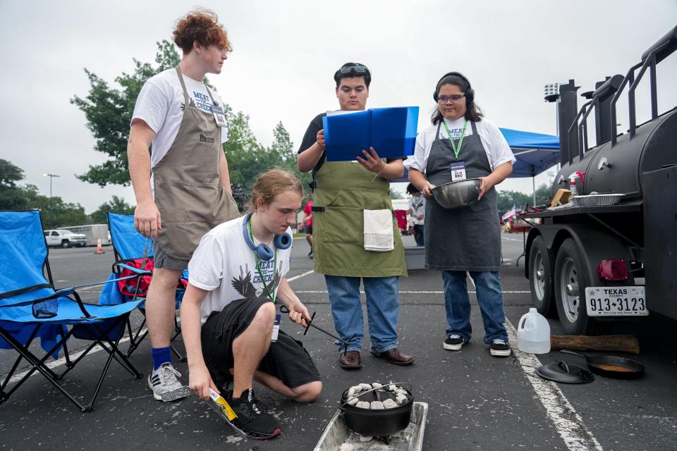 Cedar Creek High's Connor Smith preheats a Dutch oven while team mates Danathan Hughston, left, Vicente Camarillo, center, and Emanuel Castillo, right, go over notes on how to make their dessert. The team's lemon orange cake won 10th place in desserts at Saturday's High School BBQ Inc. state competition.