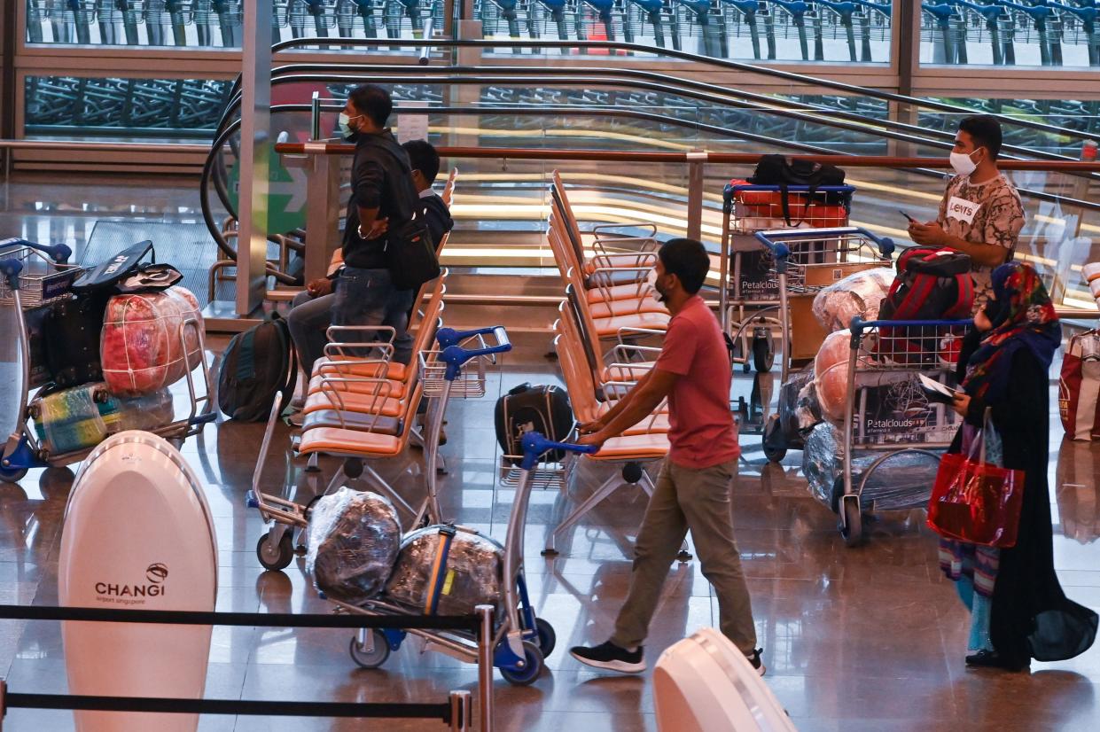 Travellers wait at departure hall before check-in at Changi International Airport in Singapore.