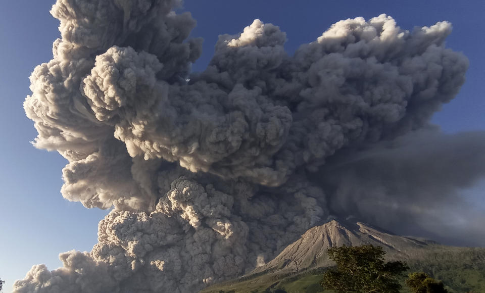 CORRECTS DATE - Mount Sinabung spews volcanic material during an eruption in Karo, North Sumatra, Indonesia, Tuesday, March 2, 2021. The 2,600-metre (8,530-feet) volcano erupted Tuesday, sending volcanic materials a few thousand meters into the sky and depositing ash on nearby villages. (AP Photo/Sastrawan Ginting)