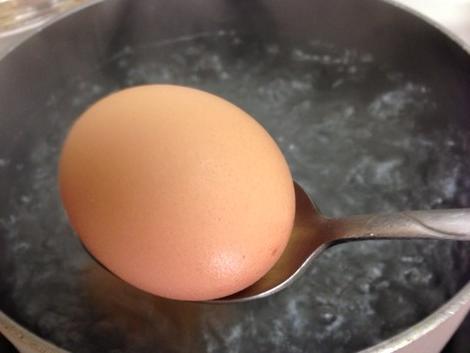 Placing the eggs in water with a spoon to avoid breaking them