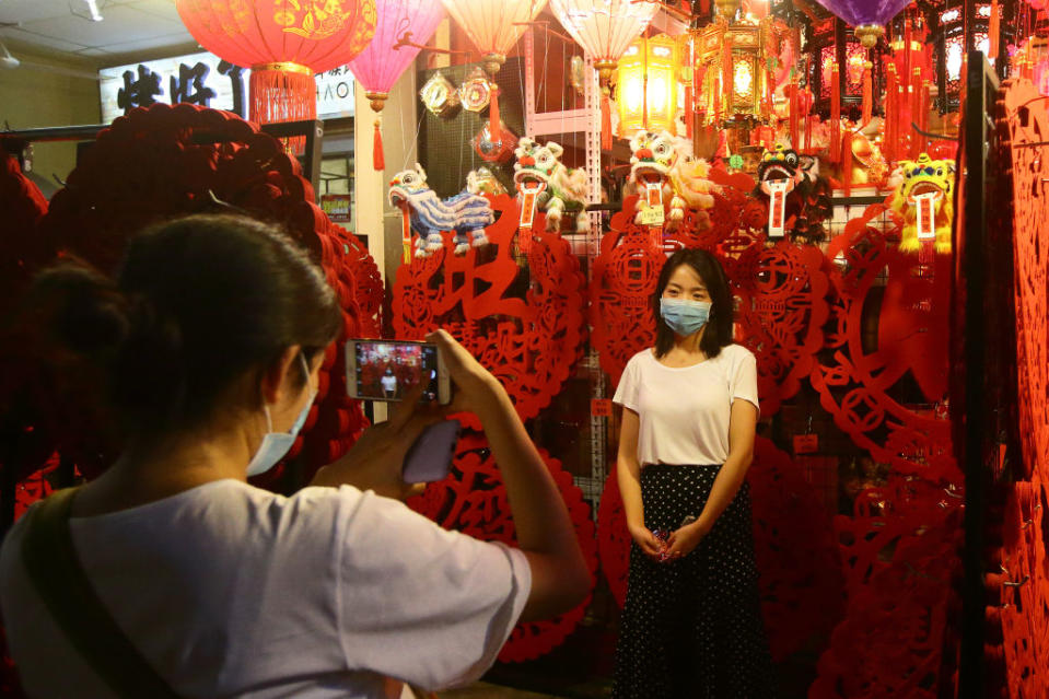 SINGAPORE - JANUARY 24:  Shoppers wear mask as they take photo with a lunar new year decoration at Chinatown  on January 24, 2020 in Singapore. Singapore confirmed another two cases of the Wuhan viruses today, making a total of three, as Singapore prepares to usher in the Year of the Rat, one of the most anticipated holidays on the Chinese calendar. Also known as the Spring festival or the Lunar New Year, the celebrations last for about 15 days.  (Photo by Suhaimi Abdullah/Getty Images)