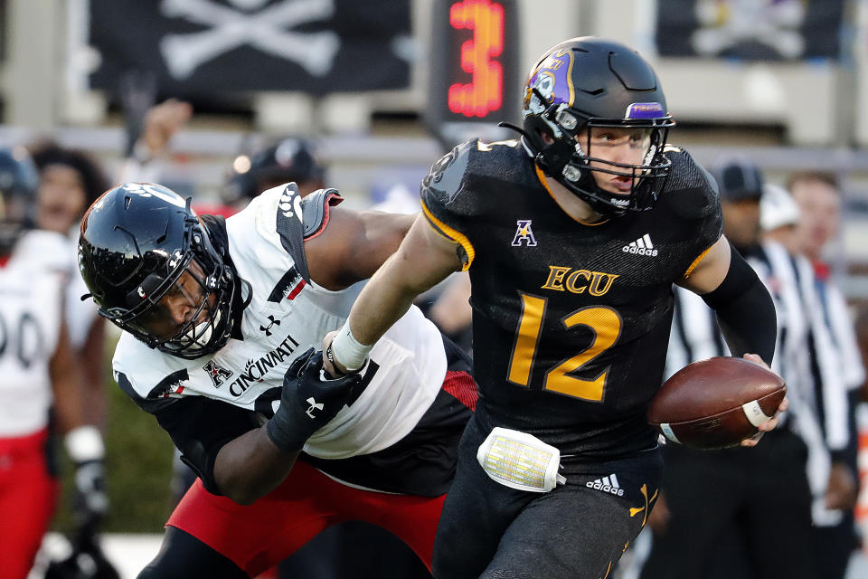 Cincinnati's Curtis Brooks (92) grabs the arm of East Carolina quarterback Holton Ahlers (12) for a sack during the first half of an NCAA college football game in Raleigh, N.C., Friday, Nov. 26, 2021. (AP Photo/Karl B DeBlaker)