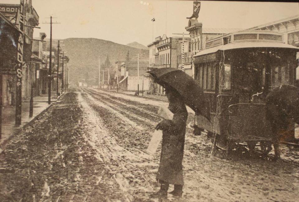 “Happy New Year” from The Tribune carrier to his customers on Jan. 1. 1890. This scene looking up Higuera Street was distributed by the Morning Tribune in postcard size to its readers on Jan 1, 1890. One of the Horse cars is at right while the heavily dressed carrier makes his way across a muddy street, with not another person in view. The Tribune, and all other newspapers published here in earlier years, frequently complained about the mud in winter and the dust in summer. [caption from August 7, 1969 Centennial edition] However note on back says looking south at about Chorro St.