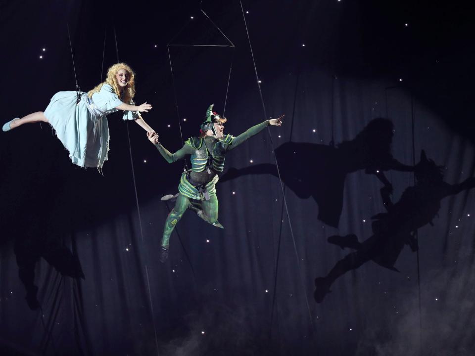 An actress and actor flying in the air in a production of Peter Pan.
