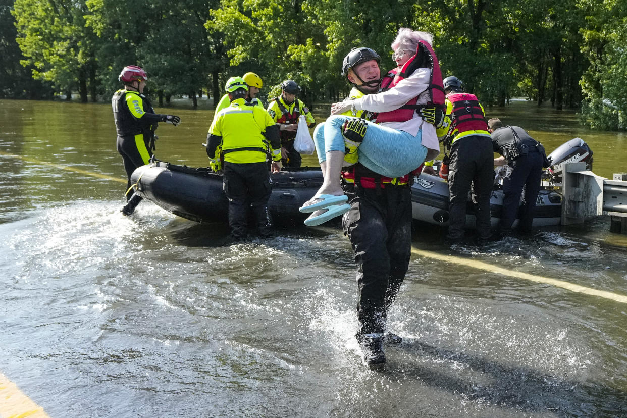 A firefighter carries a woman who was evacuated in a boat through floodwaters.