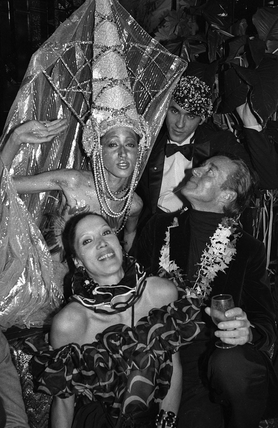 Model Pat Cleveland in costume with Halston, Martin Snaric, and Marina Schiano at Régine’s Rio Carnival party in New York on March 3, 1980. - Credit: Dustin Pittman/WWD