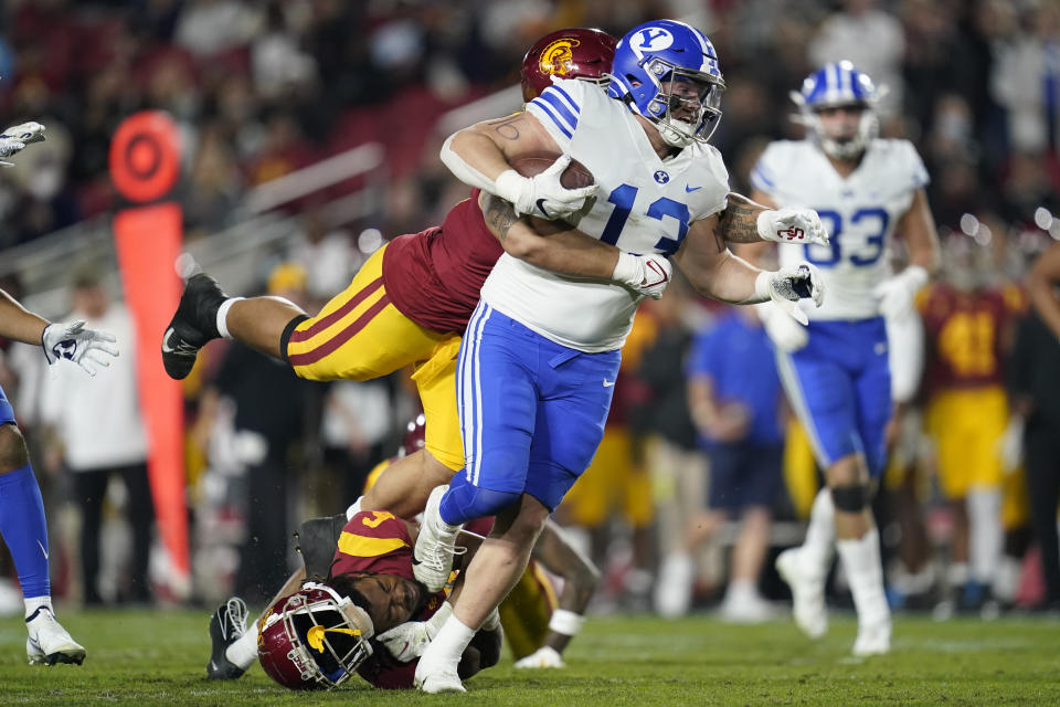 Brigham Young tight end Masen Wake (13) is tackled by Southern California cornerback Isaac Taylor-Stuart, bottom left, and defensive lineman Stanley Ta'ufo'ou (47) during the first half of an NCAA college football game in Los Angeles, Saturday, Nov. 27, 2021. (AP Photo/Ashley Landis)