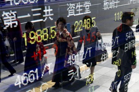 Women wearing Hakama, or Japanese traditional Kimono, are reflected in an electronic board, showing various stock prices, outside a brokerage in Tokyo, March 23, 2015. REUTERS/Yuya Shino