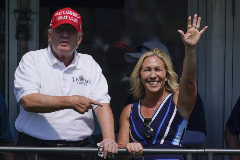 FILE - Rep. Marjorie Taylor Greene, R-Ga., waves while former President Donald Trump points to her while they look over the 16th tee during the second round of the Bedminster Invitational LIV Golf tournament in Bedminster, N.J., July 30, 2022. Republicans ranging from Senate Minority Leader Mitch McConnell to Marjorie Taylor Greene defended Trump against an unprecedented FBI search. (AP Photo/Seth Wenig, File)