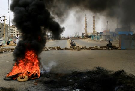 Sudanese protesters are seen near burning tyres used to erect a barricade on a street, demanding that the country's Transitional Military Council handover power to civilians, in Khartoum