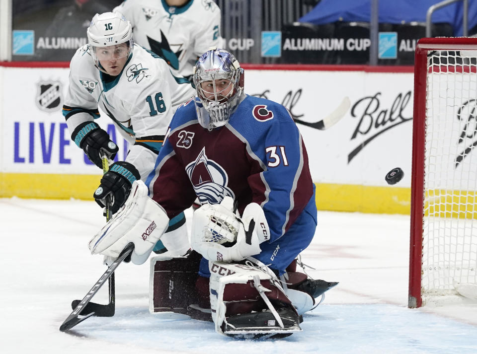 San Jose Sharks center Ryan Donato, back, redirects a shot past Colorado Avalanche goaltender Philipp Grubauer and wide of the goal during the third period of an NHL hockey game Tuesday, Jan. 26, 2021, in Denver. (AP Photo/David Zalubowski)