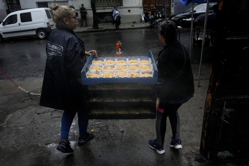 FILE - Volunteers carry stackable crates filled with hot meals provided by the Excluded Workers Movement's soup kitchen, in Buenos Aires, Argentina, March 13, 2024. Social organizations that run soup kitchens in Argentina have criticized cutbacks by President Javier Milei’s government amid skyrocketing poverty levels. (AP Photo/Natacha Pisarenko, File)