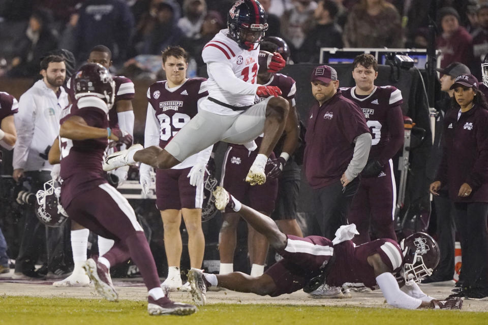 Mississippi wide receiver Dontario Drummond (11) leaps over a fallen Mississippi defender for a first down during the first half of an NCAA college football game, Thursday, Nov. 25, 2021, in Starkville, Miss. (AP Photo/Rogelio V. Solis)