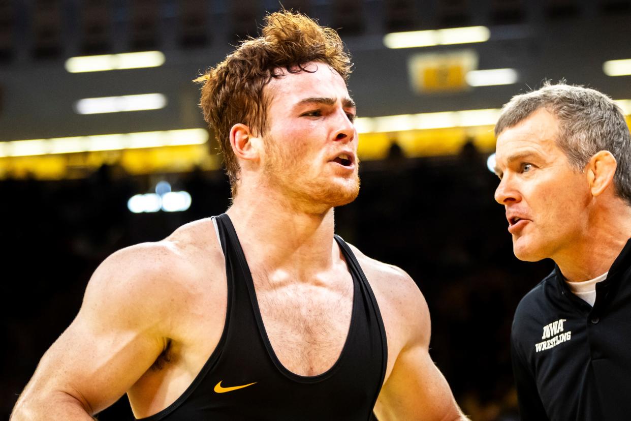 Iowa's Michael Caliendo, left, is greeted by head coach Tom Brands after winning his 165-pound match against Oregon State on Nov. 19 in Iowa City.