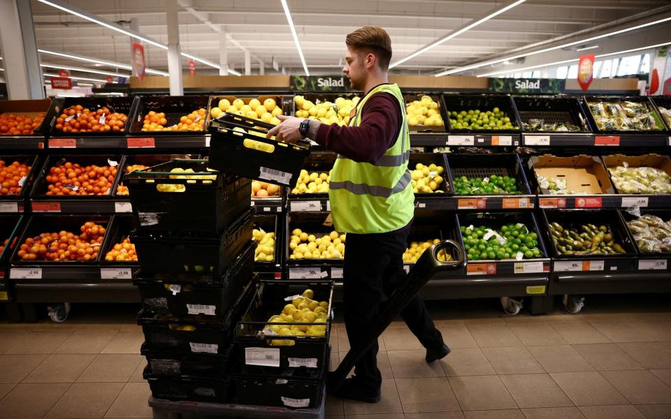 A Sainsbury's employee arranges produce inside a supermarket in Richmond, west London