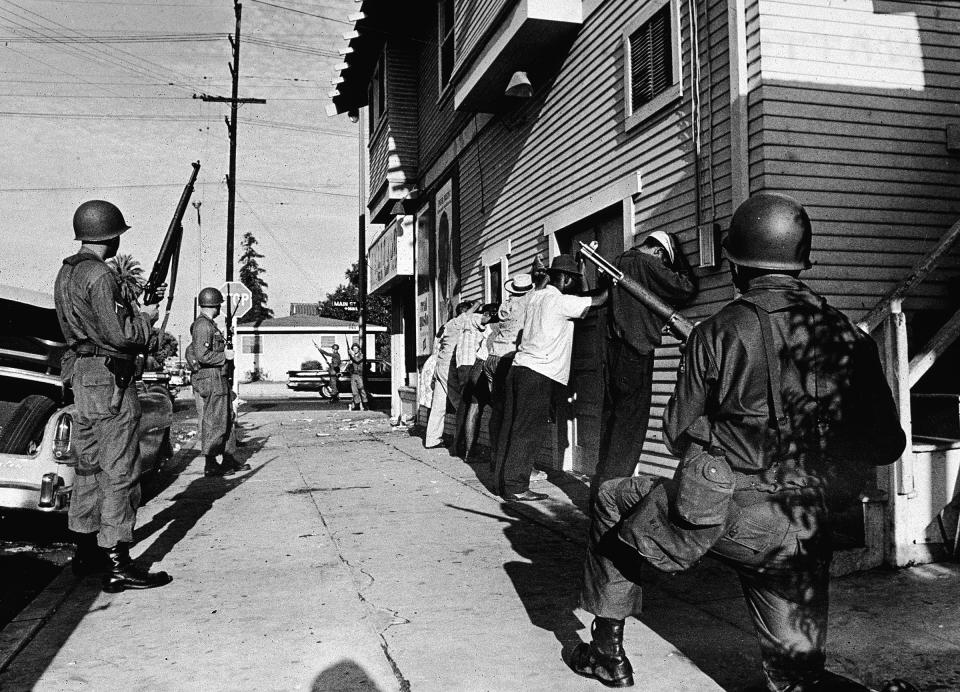 Armed National Guardsmen force a line of Black men to stand against the wall of a building during the Watts riots in 1965 | Hulton Archive/Getty Images