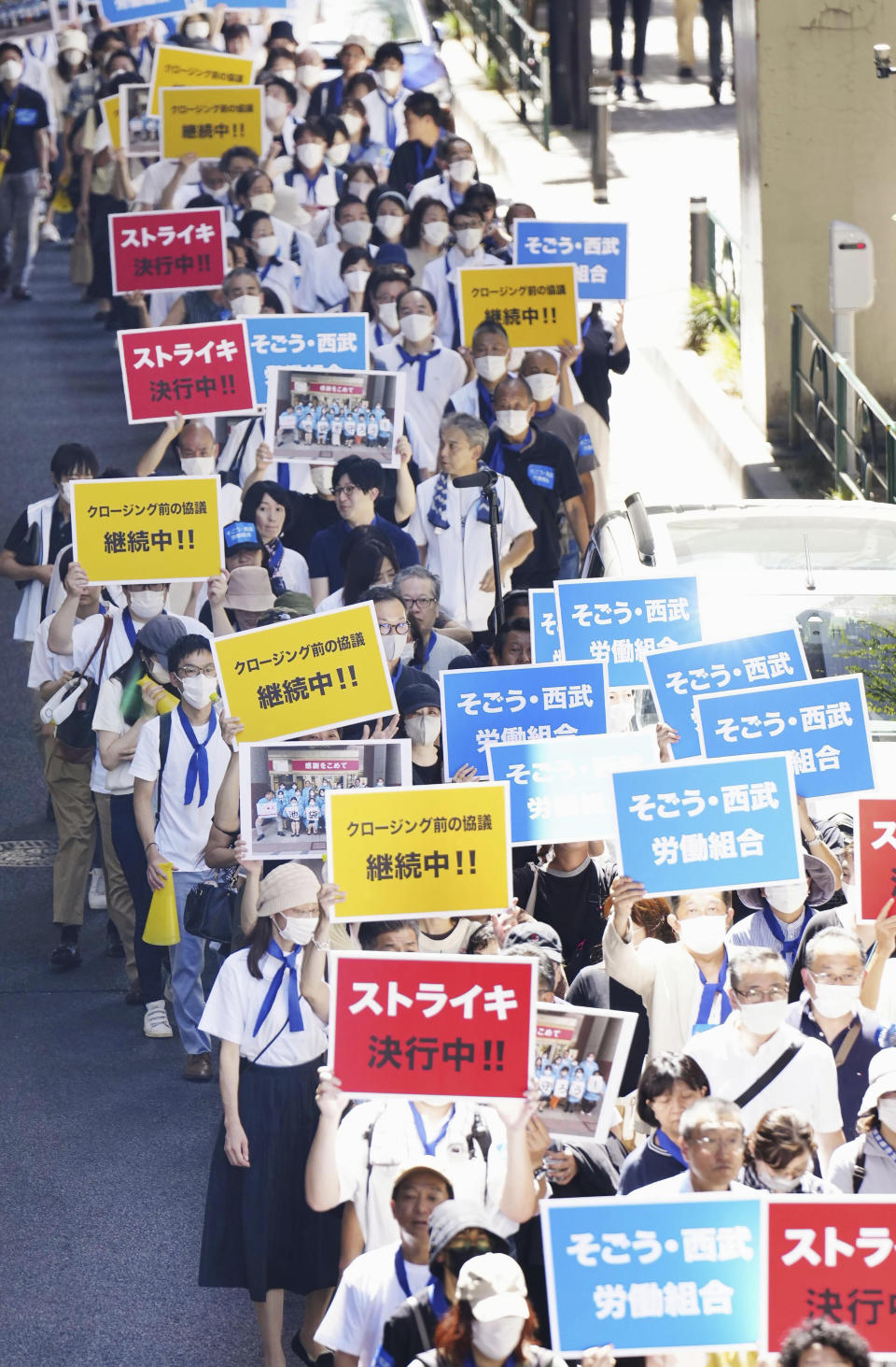 Labor union members of Japanese department store operator Sogo & Seibu march during a strike in Tokyo Thursday, Aug. 31, 2023. They stage a rare strike at its flagship store in Tokyo over job security concerns, as its parent company plans to sell the chain to a U.S. fund despite the union's opposition. The banners read "On strike," red, "Sogo & Seibu Labor Union," blue. (Kyodo News via AP)