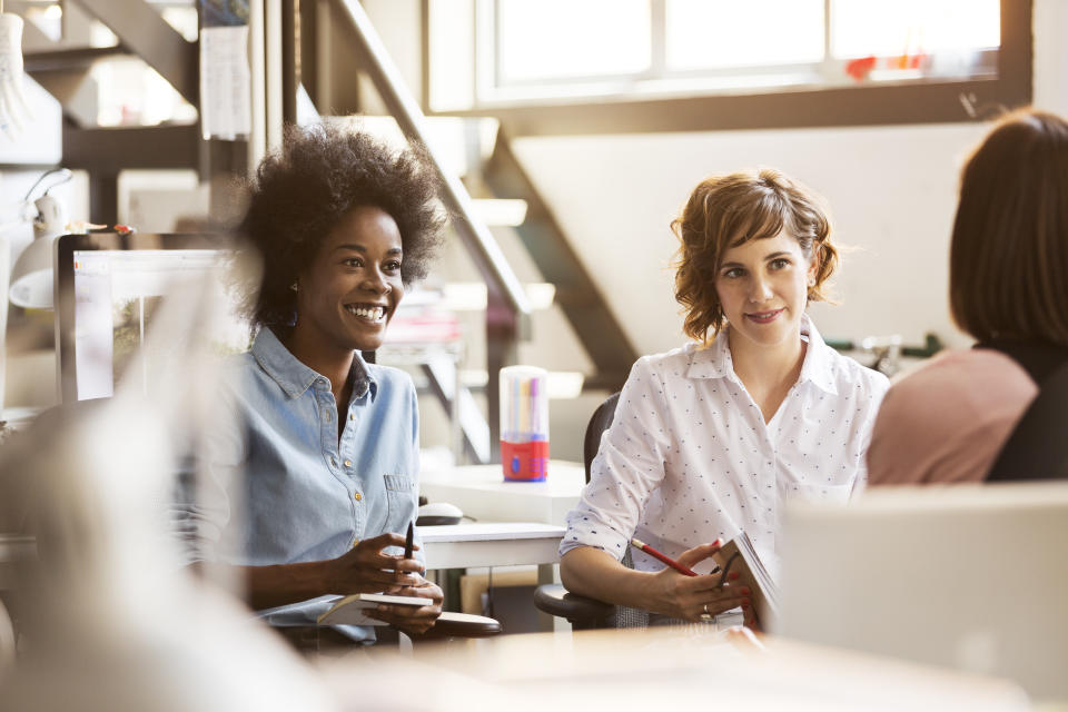 Happy businesswomen discussing with female colleague in office