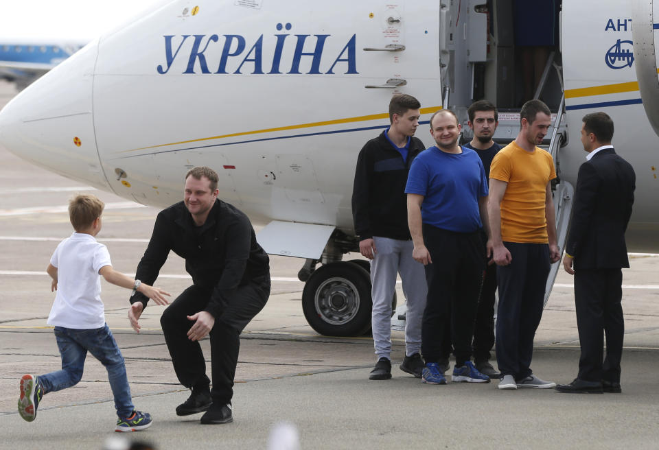 Ukraine's President Volodymyr Zelenskiy, right, greets Ukrainian prisoners upon their arrival at Boryspil airport, outside Kyiv, Ukraine, Saturday, Sept. 7, 2019. Planes carrying prisoners freed by Russia and Ukraine have landed in the countries' capitals, in an exchange that could be a significant step toward improving relations between Moscow and Kyiv. The planes, each reportedly carrying 35 prisoners, landed almost simultaneously at Vnukovo airport in Moscow and at Kyiv's Boryspil airport. (AP Photo/Efrem Lukatsky)