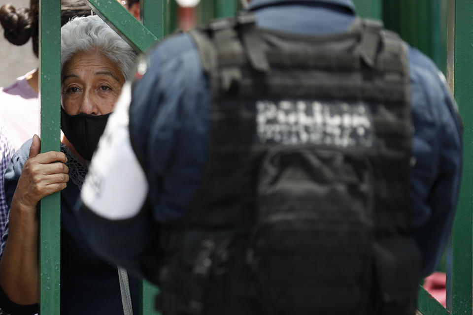 A woman peers through the gates of a public hospital treating both COVID-19 and other patients, as she tries to get information about a hospitalized loved one, in the Iztapalapa district of Mexico City, Tuesday, May 5, 2020. Iztapalapa has the most confirmed cases of the new coronavirus within Mexico's densely populated capital, itself one of the hardest hit areas of the country with thousands of confirmed cases and around 500 deaths.(AP Photo/Rebecca Blackwell)
