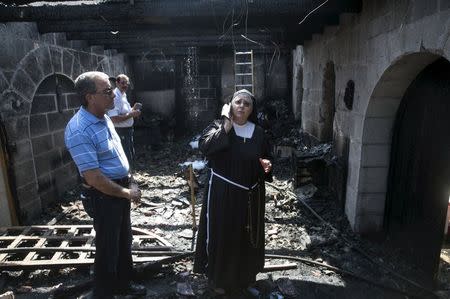 A nun stands at the scene of a fire in the Church of Loaves and Fishes on the shores of the Sea of Galilee in northern Israel June 18, 2015. REUTERS/Baz Ratner