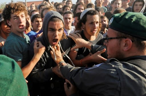 An Israeli police officer scuffles with activists as colleagues begin evicting 15 families from the Netiv Haavot settlement outpost in the occupied West Bank on June 12, 2018 in accordance with a Supreme Court order