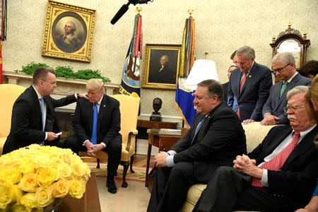 President Donald Trump closes his eyes in prayer along with Pastor Andrew Brunson, after his release from two years of Turkish detention, along with Secretary of State Mike Pompeo and National Security Advsior John Bolton, in the Oval Office of the White House, Washington, U.S., October 13, 2018. REUTERS/Mike Theiler