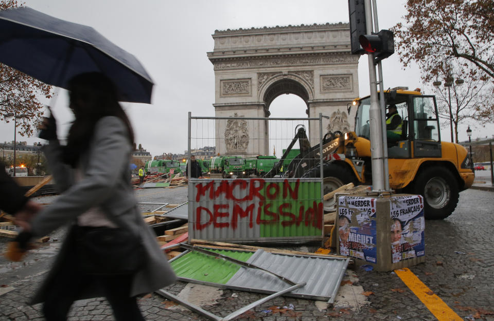 A bulldozer cleans the street from a barricade in the aftermath of a protest against the rising of the fuel taxes at the Champs Elysees avenue in Paris, France, Sunday, Nov 25, 2018. French President Emmanuel Macron has condemned violence by protesters at demonstrations against rising fuel taxes and his government. Tag on the barricade reads, "Macron resignation". (AP Photo/Michel Euler)