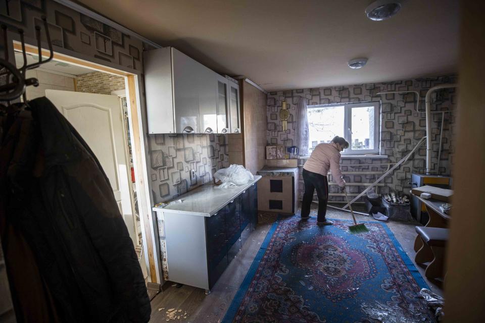 a woman sweeps broken glass and debris