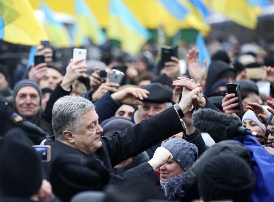 Ukrainian President Petro Poroshenko, left, greets people gathered to support independent Ukrainian church near the St. Sophia Cathedral in Kiev, Ukraine, Saturday, Dec. 15, 2018. Ukraine's Orthodox clerics gather for a meeting Saturday that is expected to form a new, independent Ukrainian church, and Ukrainian authorities have ramped up pressure on priests to support the move. (AP Photo/Efrem Lukatsky)