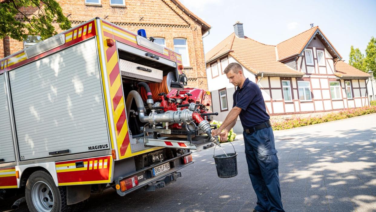 Einsatzkräfte der Freiwilligen Feuerwehr zapfen Löschwasser aus dem Tank eines ihrer Einsatzfahrzeuge.