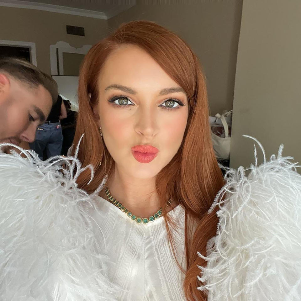 Lindsay Lohan pouts for the camera while wearing a white dress with feathery sleeves