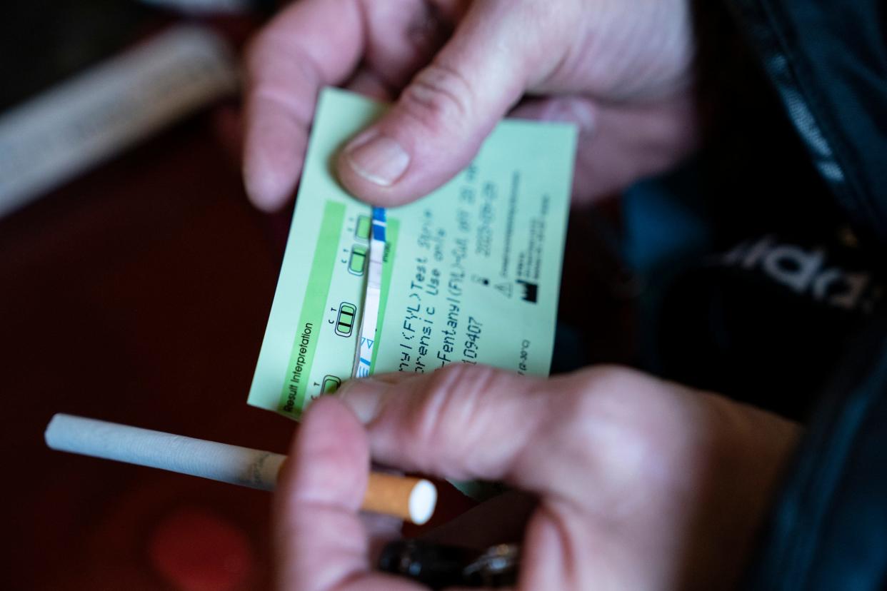 A visitor to Amanda's Detroit east-side bungalow looks at a fentanyl test strip after dipping the strip into heroin residue left in a cooker on Monday, May 2, 2022. The strip appears to be positive for fentanyl.