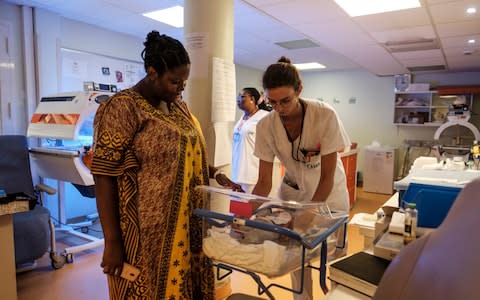 Claire Crepin, a midwife, holds the newborn son of Ahmada Moustafa (Left) for a checkup.  - Credit: Eduardo Soteras Jalil /The Telegraph