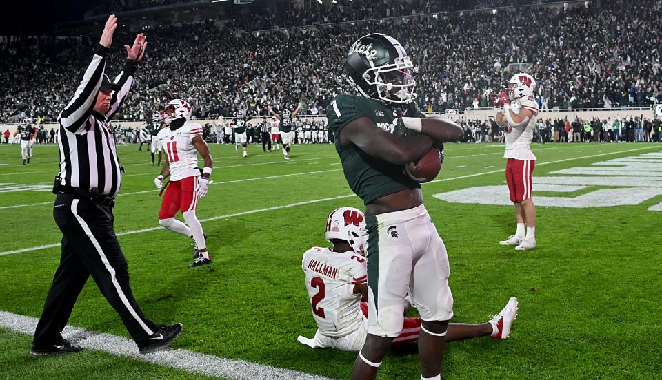 Oct. 15, 2022; East Lansing, Michigan; Michigan State Spartans wide receiver Jayden Reed (1) catches a touchdown pass in spite of Wisconsin Badgers cornerback Ricardo Hallman (2) in a second overtime period to win the game, 34-28, at Spartan Stadium. Dale Young-USA TODAY Sports